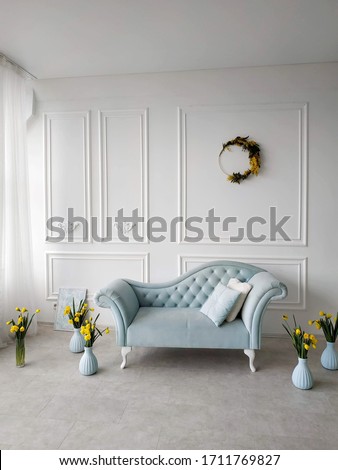 blue sofa with a carriage tie in the Baroque style in the photo Studio. in the interior of a figured vase with the daffodils.