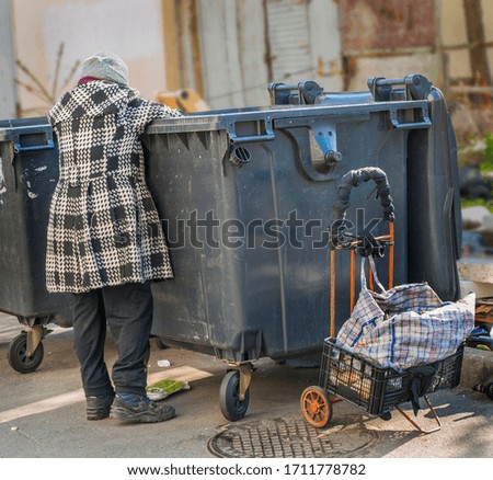 City beggar rummages in a trash can