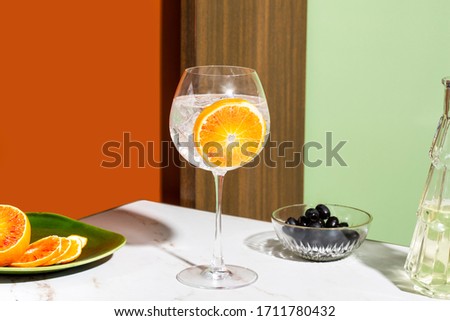 Gin tonic cocktail, garnished with orange slice, colorful background Royalty-Free Stock Photo #1711780432