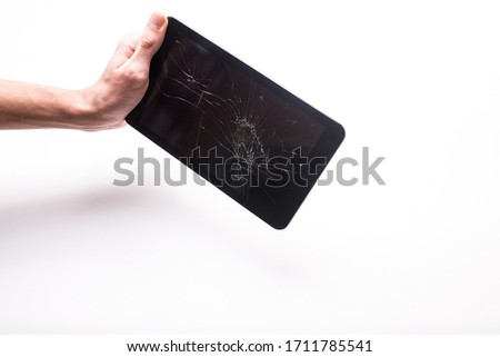 Black broken tablet on a white background. Cracked gadget screen. The guy holds a broken tablet in his hand.