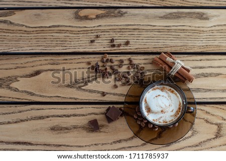 cup of coffee with milk foam and cinnamon on a table of light wood. Top view, copy space.