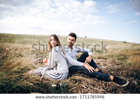 Beautiful loving couple sitting on grass. The guy and the girl hipster travel