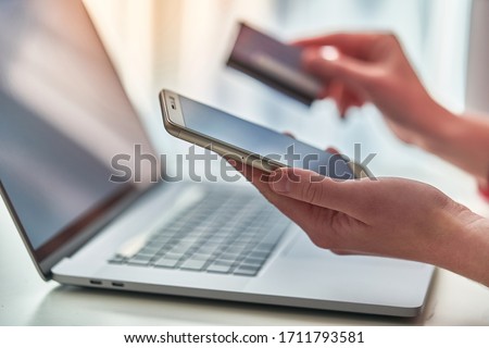 Person using laptop, plastic credit card and mobile phone for online shopping and paying goods. Modern people using e commerce and mobile payment banking  Royalty-Free Stock Photo #1711793581