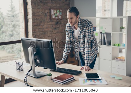 Photo of handsome business guy look computer monitor table waiting colleagues partners answer seriously reading report wear casual shirt standing modern office indoors