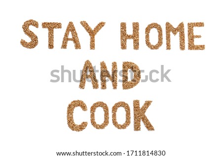 Stay home concept of self-isolation during the Covid-19 coronavirus pandemic. The inscription "Stay home and cook" in Latin script made of buckwheat. What to do during quarantine