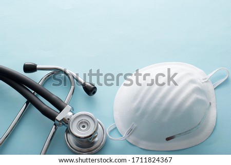 Surgical mask with stethoscope conceptual of the Covid-19 and coronavirus pandemic in a high angle view over a white background