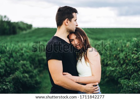 Young loving couple gently hugging on the background of green currant plantations. Love Story.