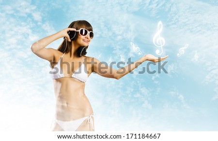 Young attractive girl in bikini wearing headphones touching media icon