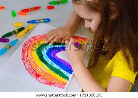Girl kid draws a rainbow during the Covid-19 quarantine at home. Children's creativity. Classes with children. Stay home, let's all be good, made during the concept of the coronavirus pandemic.