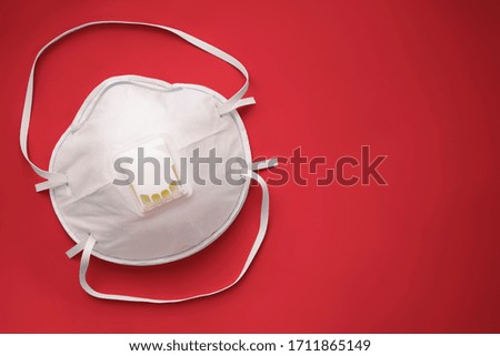 White face medical mask against virus, flu and coronavirus isolated on red background. Protective respirator with valve. Royalty-Free Stock Photo #1711865149