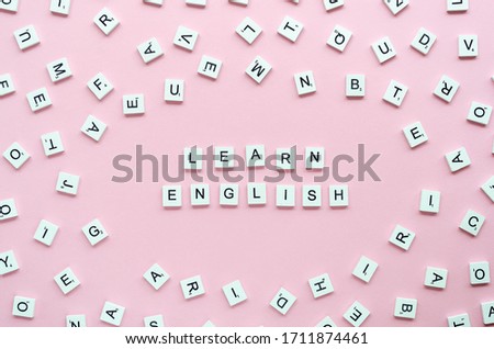 Top view words LEARN ENGLISH written with wooden cube letters on a pink background. Say and study at home