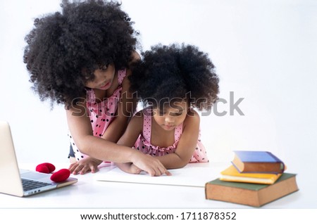 Dark skinned elder sister teaching little sister for homework, spending time together