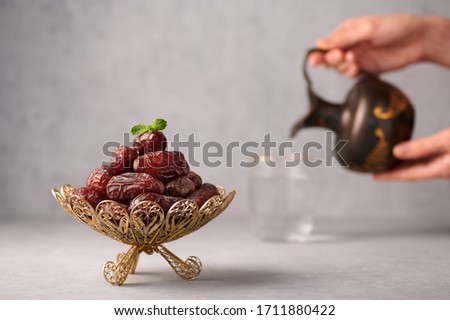 Date Fruits or Kurma in vintage arabic dish and jug of water at grey concrete background. Dates and water is Ramadan meal. Ramazan Iftar food. Royalty-Free Stock Photo #1711880422