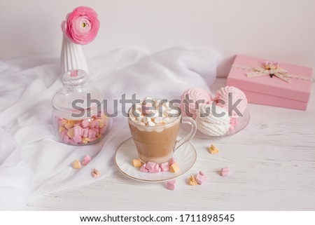 good morning card in pink. A Cup of coffee, a marshmallow and a pink flower on a light wooden background.