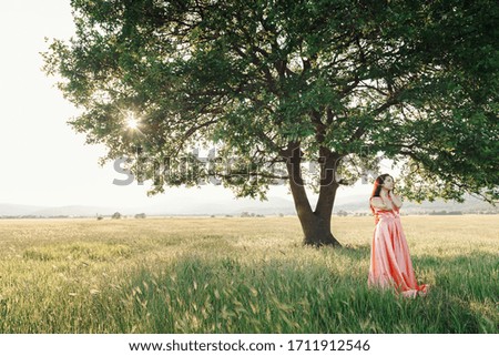 Beautiful Active Free Girl on Summer Green Outdoor Background. girl dancing in a field in a beautiful pink dress by a mighty oak