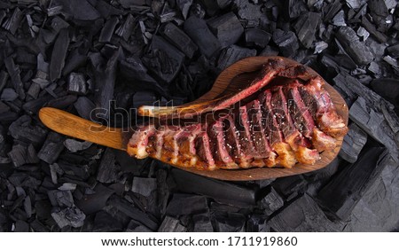 grilled tomahawk steak on wooden plate ready for eat. On background coal Royalty-Free Stock Photo #1711919860