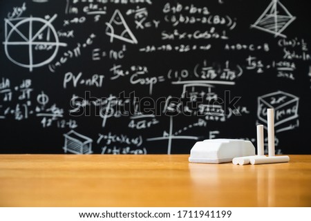 Education background concept. Board eraser and chalk on the wooden table with blackboard with many Mathematical formula.