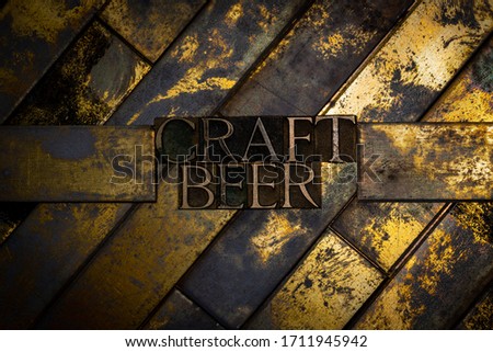 Photo of real authentic typeset letters forming Craft Beer text on vintage textured grunge copper and gold background