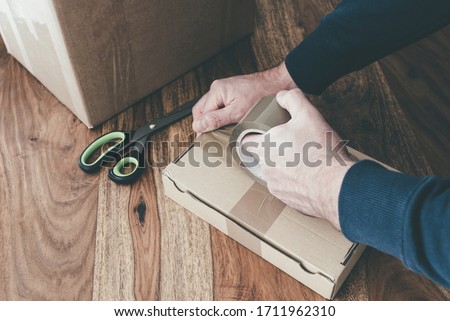 close-up of person sealing up shipping box with parcel tape, pruchase return and return of goods concept Royalty-Free Stock Photo #1711962310