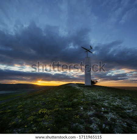 Figurine of a paraglider on a pedestal with a beautiful sunset sky and flowers
