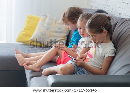Children sit on the couch and play games on the tablet and watch cartoons, the concept of children's Internet addiction