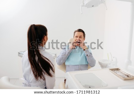 back view of african american dentist sitting near scared patient touching face