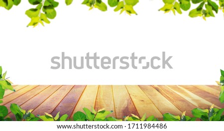 Brown blank wooden table top with spring green leaves as frame and free space for text or montage your products.