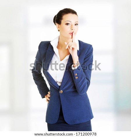 Portrait of attractive business woman with finger on lips, gesturing for quiet 