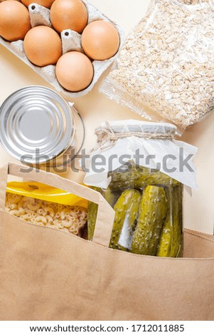 Paper craft bag with various products. Cereals, eggs, canned food. Food donation, delivery service concept. Top view, copyspace. Food supplies crisis stock for isolation period.