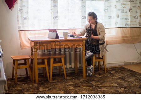 A young girl sits at home in self-isolation and works remotely at home, with finance charts. Communicates via video connection.
