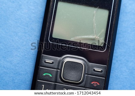 old push-button cell phone on blue background