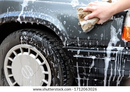 Man washing a car. Hand with foam sponge. Clouse up washing a car. Cleaning a car.