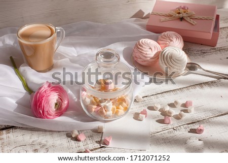 good morning card in pink. A Cup of coffee, a marshmallow and a pink flower , an empty piece of paper, a note , space for text on a light wooden background.