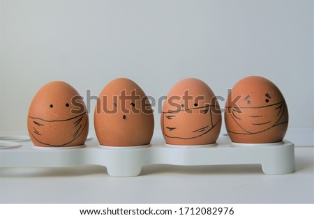 a group of four faced eggs in medical protective masks
