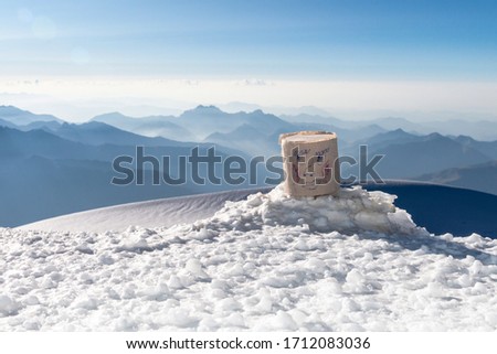 face paper roll on the background of mountain peaks, clear blue sky, sunny day and white snow in the foreground.
