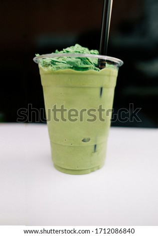 Blurry image Matcha, a cup of green tea blended on the table in  coffee shop at market.