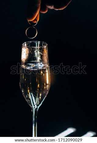 Wedding rings are falling in a glass with champagne. Creative idea how to take a picture of wedding rings.
