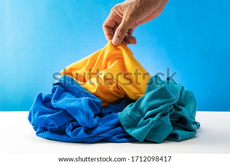 Hand holding dirty laundry on white table Blue background