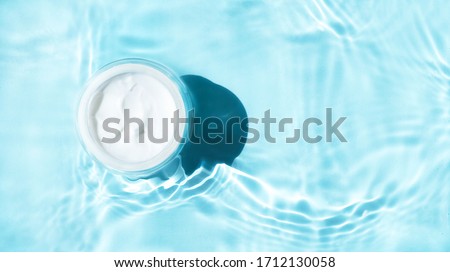 Beauty cream jar and  
bright ligh blue water. Moisturizing beauty cream, skincare and spa cosmetics. Top  view and copy space  Royalty-Free Stock Photo #1712130058