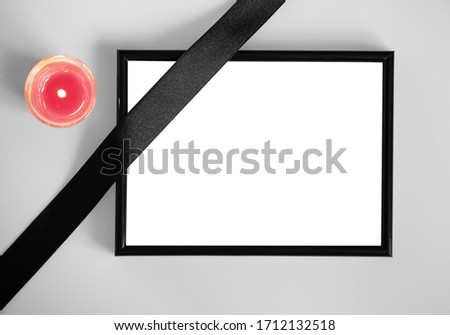 Black frame with funeral ribbon and candle, top view: space for text