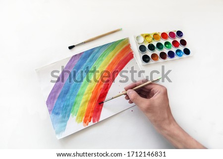 rainbow draws watercolors hand of a teenager on white paper, on a white background