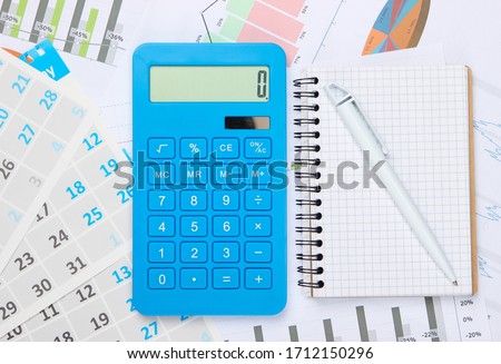 Calculator with notebook, graphs and charts, monthly calendar. Economic calculation, costing. Business and Finance