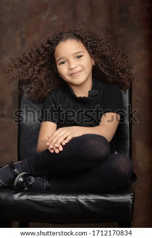 Portrait of  healthy attractive mixed race little girl with curly ringlets hairstyle and pretty face posing indoor looking at camera. Natural beauty innocence and new generation concept.
