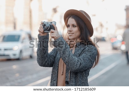 Beautiful brunette tourist girl holds a camera in her hands and looks into the lens