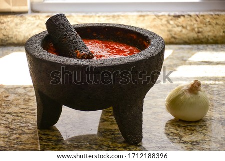Spicy red sauce made with tomato in a Traditional Mexican molcajete at kitchen Royalty-Free Stock Photo #1712188396