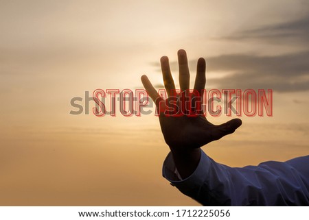 The concept of stop addiction.Hand towards the sunset background and the inscription Stop Addiction.