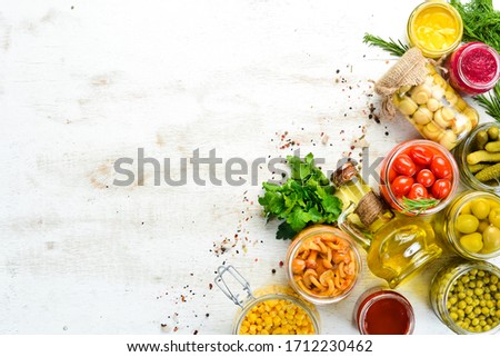 Background of food stocks in glass jars. Pickled vegetables and mushrooms. Top view.