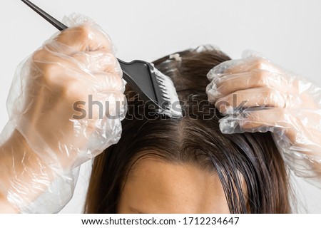 Closeup woman hands dyeing hair using a black brush. Colouring of white hair at home. Royalty-Free Stock Photo #1712234647
