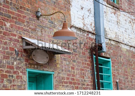 An old light fixture, corrugated metal, rusty pipes and colorful paint give an old brick building a chic industrial look.