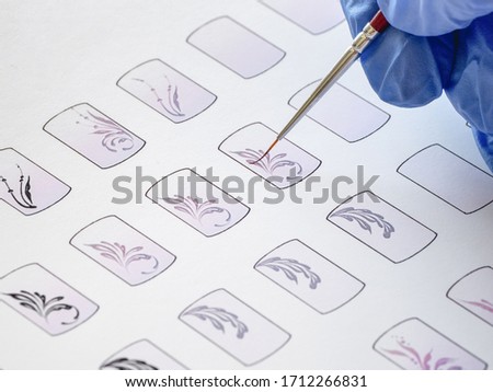 Training in painting monograms for manicure. Training cards for manicure, close up. 